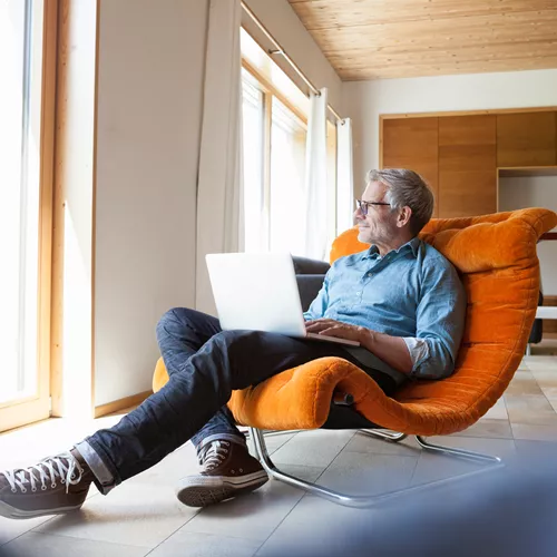 Man relaxing in the chair with his laptop | Homme se relaxant dans son fauteuil avec son ordinateur portable