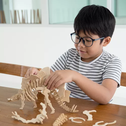 Landscape image of child wearing glasses whilst playing on the kitchen table