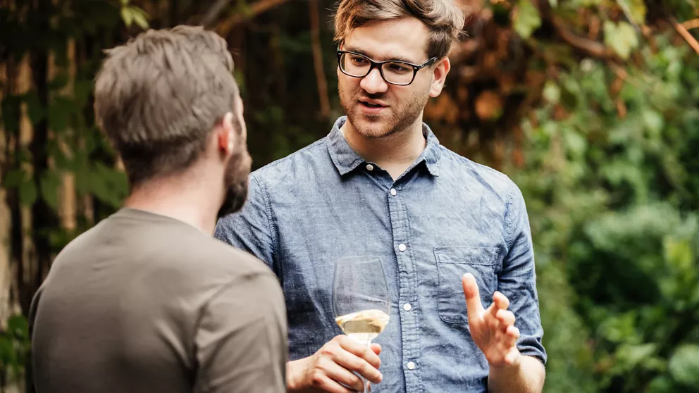 Two men talking outdoors | Deux hommes discutant à l'extérieur