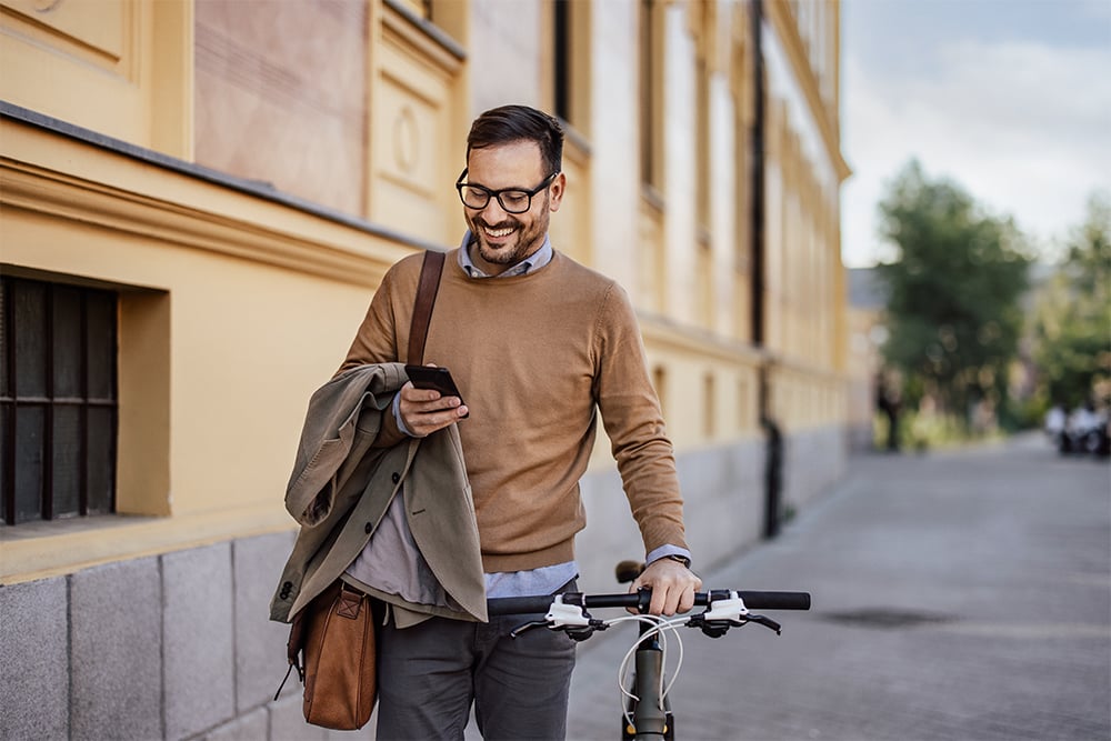 Man with glasses walking while smiling at his phone